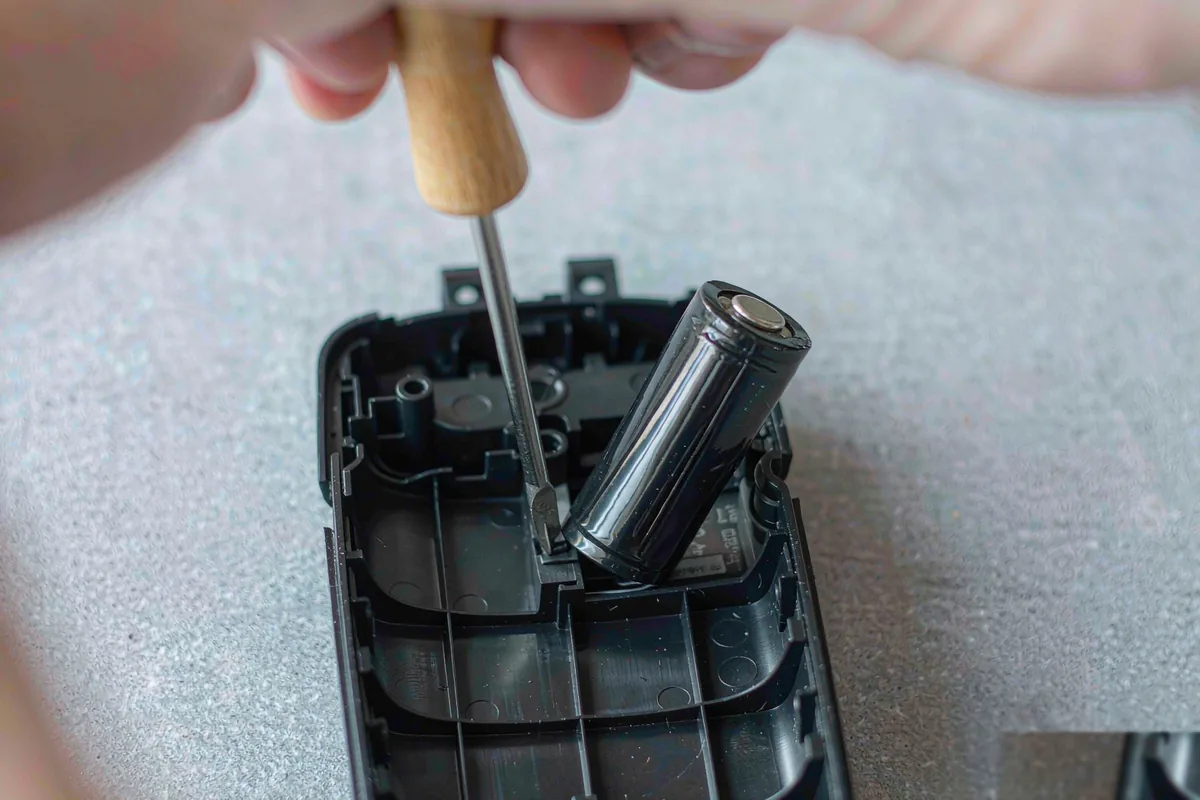 Disposable vape battery being lifted out of a device shell with a screwdriver, illustrating the EU Battery Regulation 20